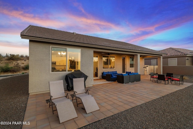 back house at dusk with outdoor lounge area and a patio area