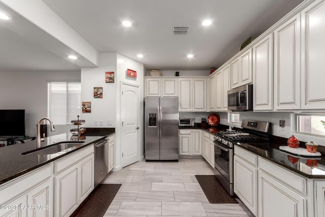 kitchen with visible vents, a sink, dark stone countertops, recessed lighting, and stainless steel appliances