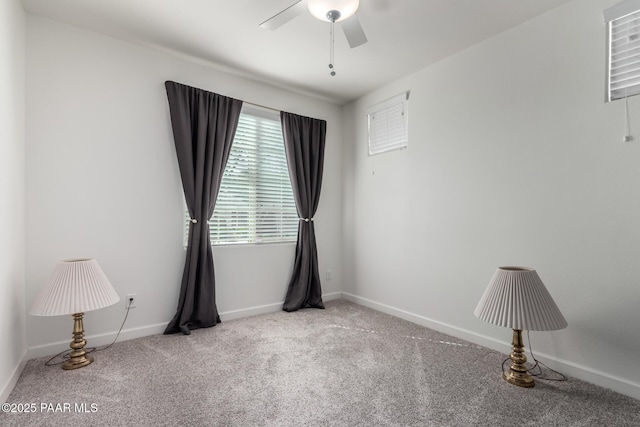 carpeted spare room featuring baseboards and a ceiling fan