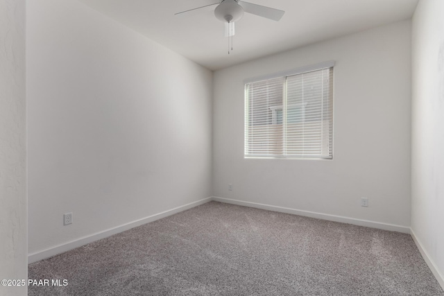 carpeted spare room with a ceiling fan and baseboards