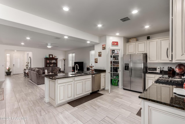 kitchen with visible vents, a sink, appliances with stainless steel finishes, a peninsula, and ceiling fan