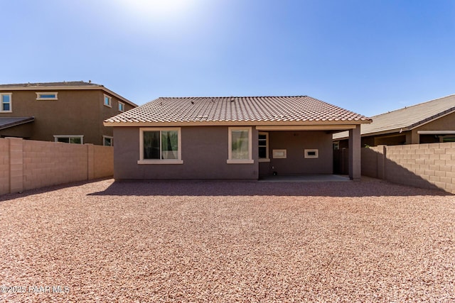 rear view of house featuring stucco siding, a patio, a tile roof, and a fenced backyard