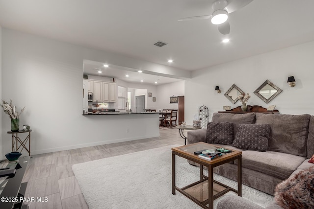 living area with visible vents, light wood-type flooring, a ceiling fan, recessed lighting, and baseboards