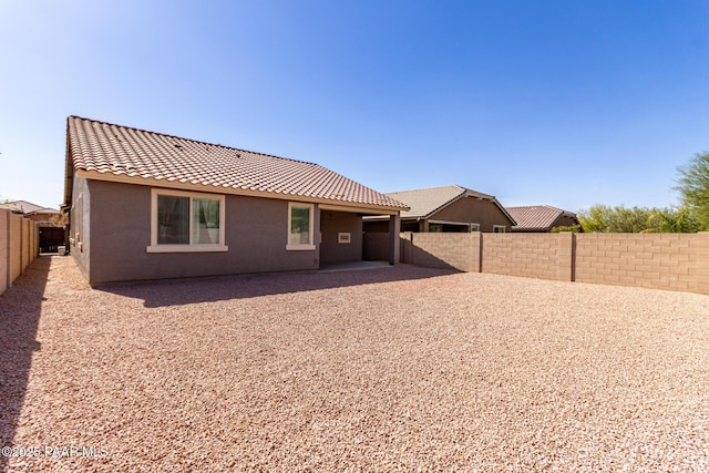 rear view of property featuring stucco siding, a patio, a fenced backyard, and a tile roof