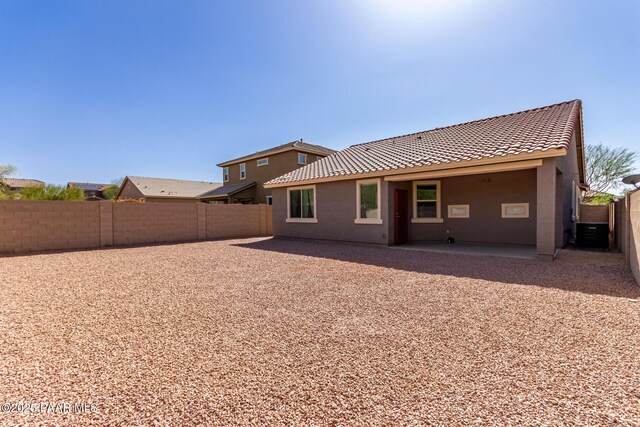 rear view of property featuring a tiled roof, central AC, stucco siding, a fenced backyard, and a patio area