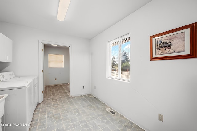 clothes washing area with washer and clothes dryer and cabinets