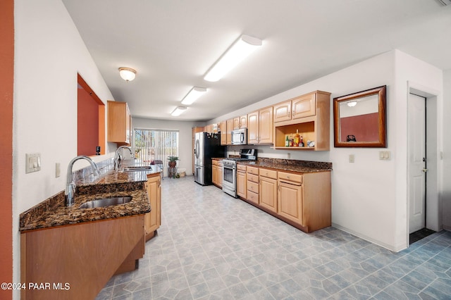 kitchen featuring sink, light brown cabinetry, stainless steel appliances, and dark stone counters