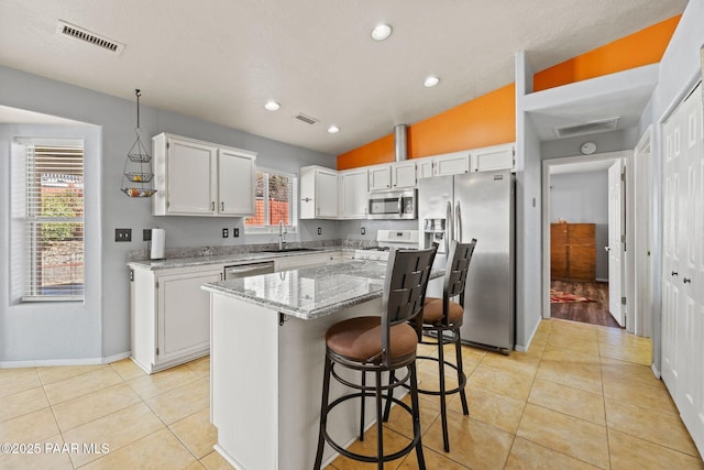 kitchen featuring appliances with stainless steel finishes, sink, a kitchen island, and white cabinets