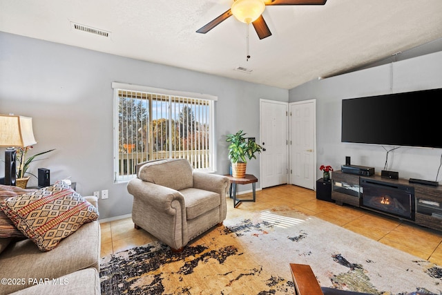 tiled living room featuring ceiling fan, vaulted ceiling, and a textured ceiling