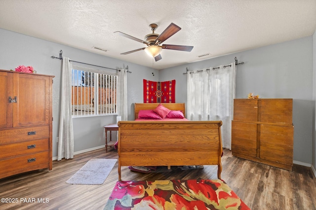 bedroom with hardwood / wood-style flooring, ceiling fan, and a textured ceiling