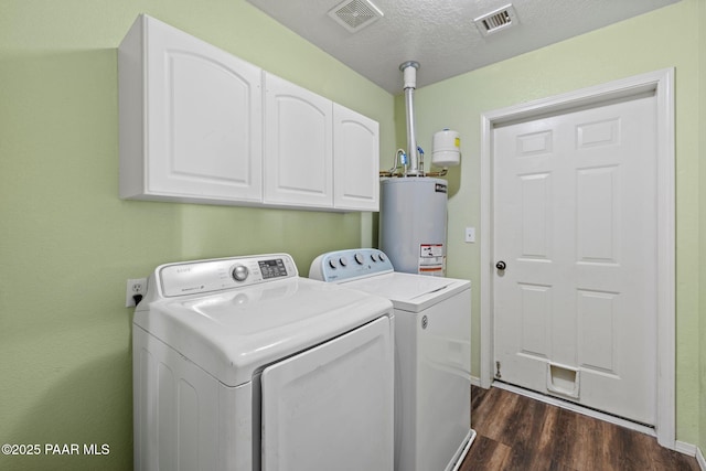 laundry room featuring dark hardwood / wood-style floors, water heater, separate washer and dryer, cabinets, and a textured ceiling