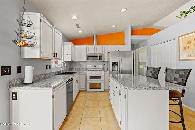 kitchen with appliances with stainless steel finishes, a center island, white cabinets, and a kitchen breakfast bar