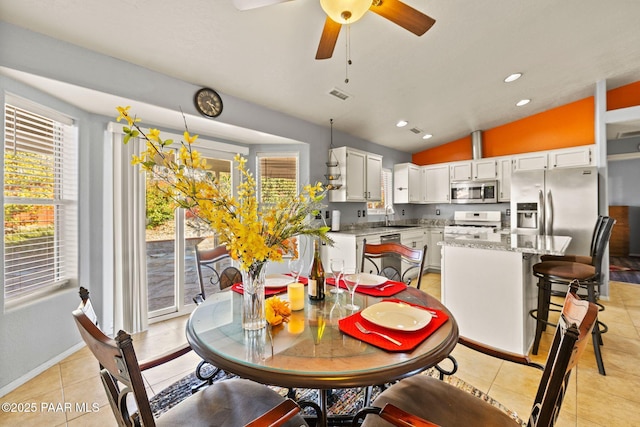 dining area with lofted ceiling, sink, light tile patterned floors, and ceiling fan