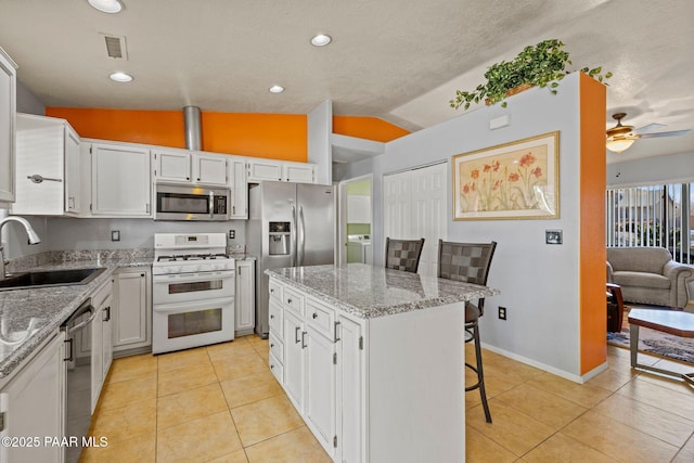 kitchen with a breakfast bar, sink, a center island, appliances with stainless steel finishes, and white cabinets