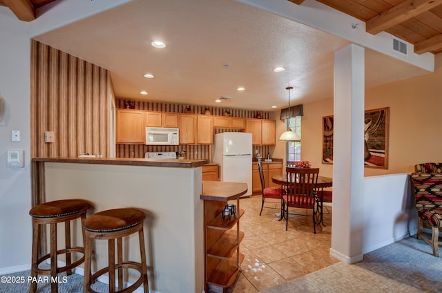 kitchen with visible vents, a peninsula, light brown cabinetry, white appliances, and recessed lighting