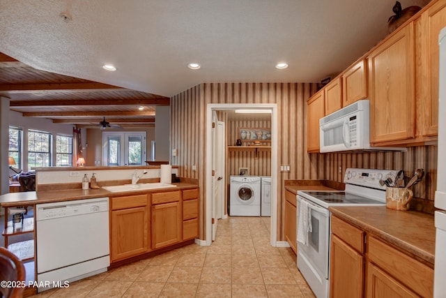 kitchen featuring a ceiling fan, washing machine and clothes dryer, a sink, a peninsula, and white appliances