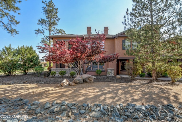 view of front facade featuring stucco siding and a chimney