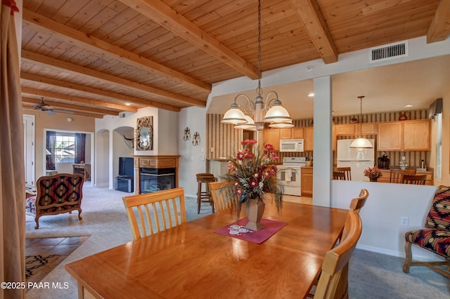 dining area with visible vents, a glass covered fireplace, beam ceiling, light colored carpet, and wood ceiling