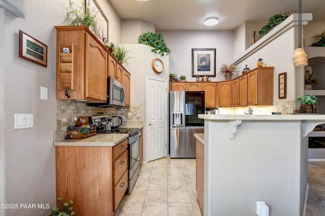 5461 N Bremont Way, Prescott Valley, AZ 86314 - kitchen with stainless steel appliances, a breakfast bar, a peninsula, tasteful backsplash, and light countertops