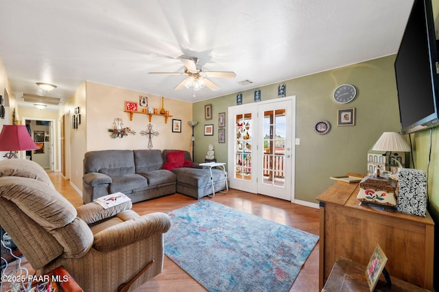 living area with ceiling fan, wood finished floors, visible vents, baseboards, and french doors