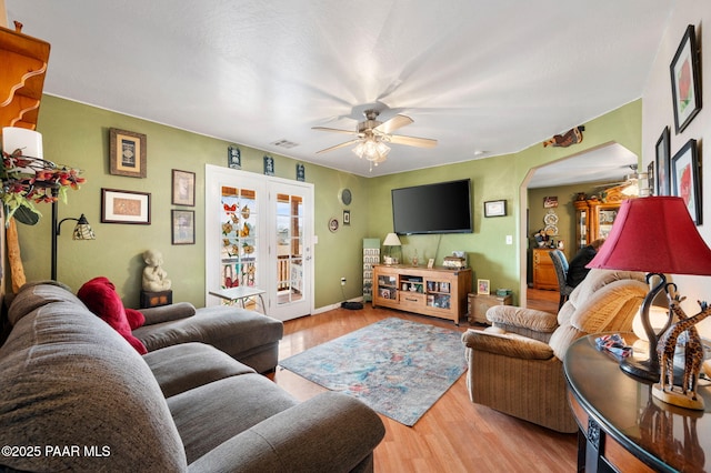 living room featuring ceiling fan, arched walkways, wood finished floors, visible vents, and french doors