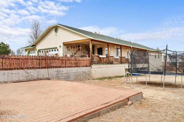 exterior space with a trampoline, fence, and a garage