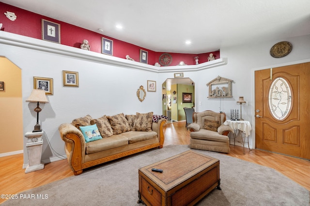 living area featuring arched walkways, baseboards, wood finished floors, and recessed lighting