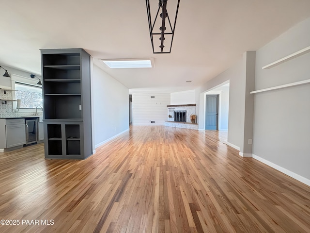 unfurnished living room featuring beverage cooler, sink, and light wood-type flooring