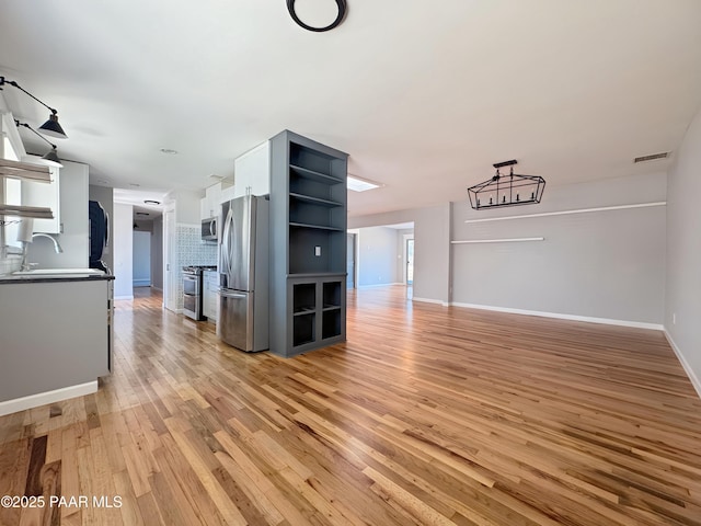 unfurnished living room with sink and light hardwood / wood-style flooring