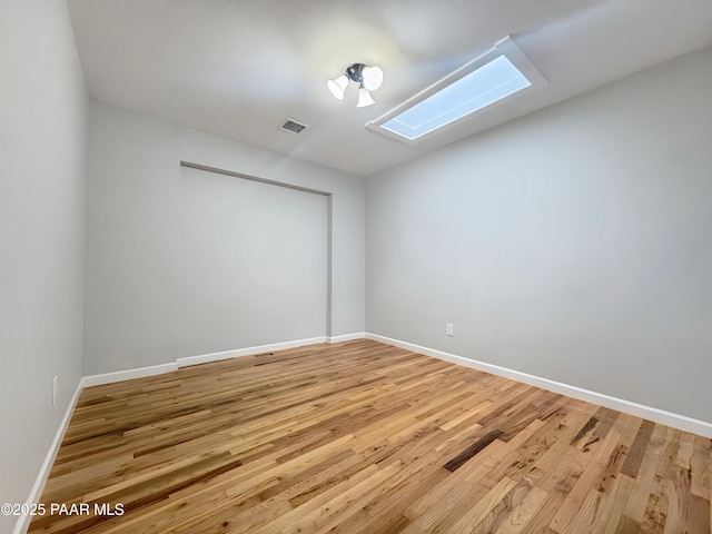 unfurnished room with wood-type flooring and a skylight