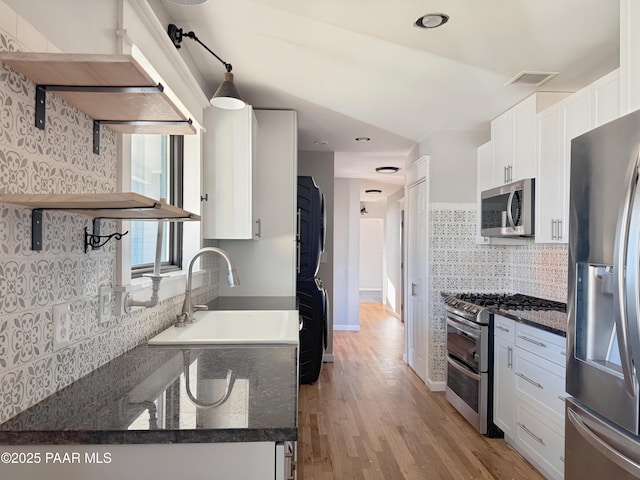 kitchen featuring white cabinetry, stainless steel appliances, sink, and dark stone counters