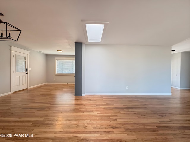 unfurnished room with a skylight and light wood-type flooring