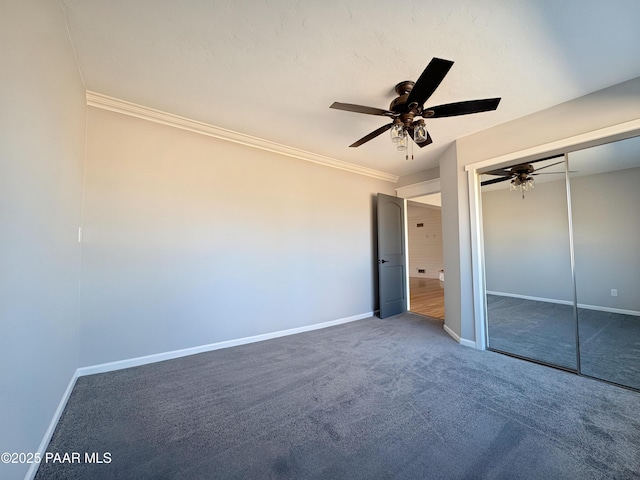 unfurnished bedroom with dark carpet, ornamental molding, a closet, and ceiling fan