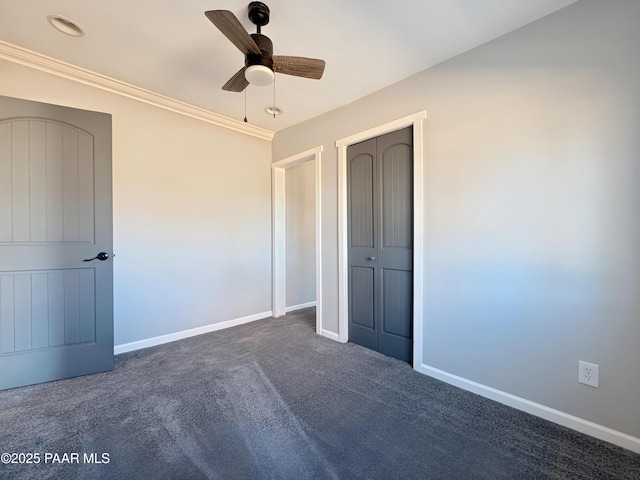 unfurnished bedroom with crown molding, ceiling fan, dark carpet, and a closet