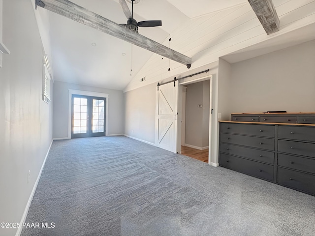 interior space featuring french doors, lofted ceiling with beams, ceiling fan, light colored carpet, and a barn door