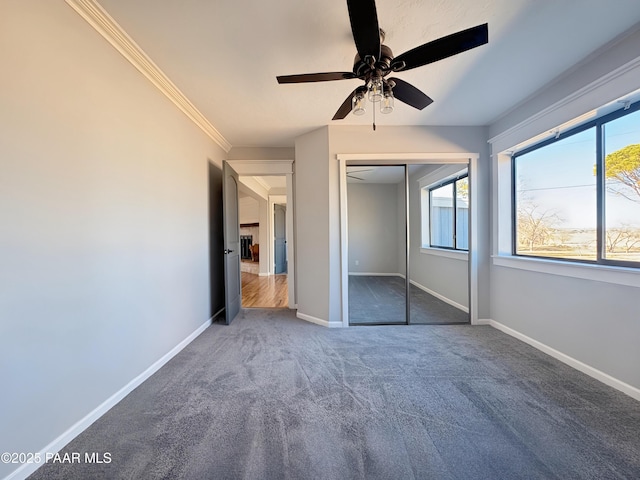 unfurnished bedroom with crown molding, a closet, ceiling fan, and carpet