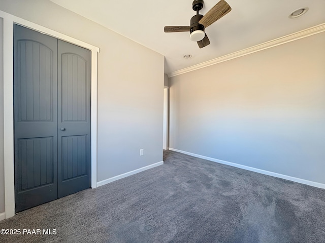 unfurnished bedroom with crown molding, ceiling fan, dark carpet, and a closet