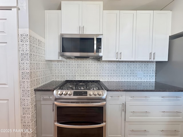 kitchen with stainless steel appliances, white cabinets, backsplash, and dark stone counters