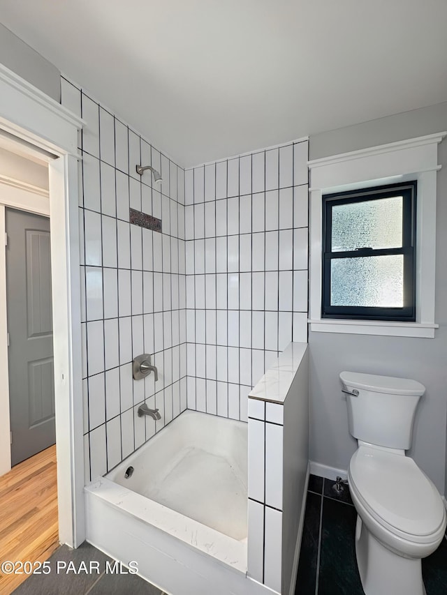 bathroom with tiled shower / bath and toilet