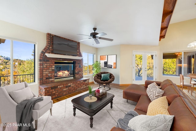 living room featuring ceiling fan, light hardwood / wood-style floors, a fireplace, and french doors