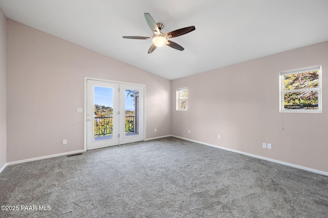 carpeted empty room featuring plenty of natural light, ceiling fan, and vaulted ceiling