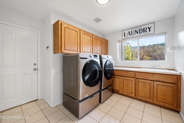 clothes washing area featuring cabinets, light tile patterned floors, sink, and washing machine and clothes dryer