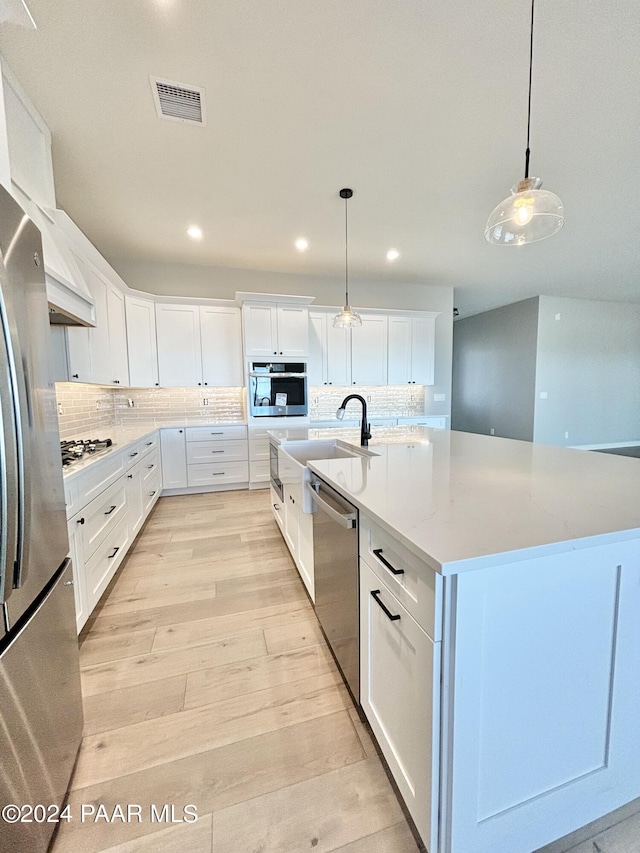 kitchen with white cabinets, a large island, stainless steel appliances, and decorative light fixtures