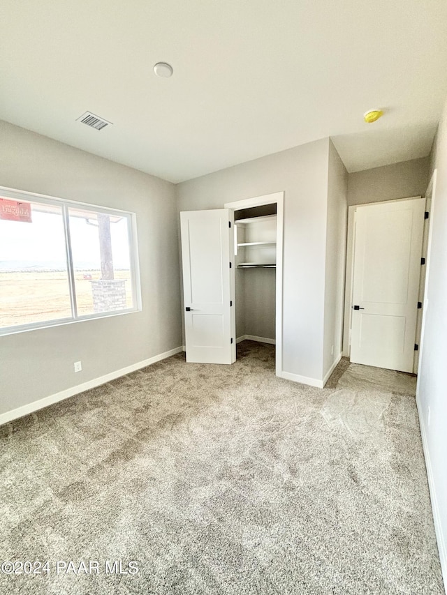 unfurnished bedroom with light colored carpet and a closet