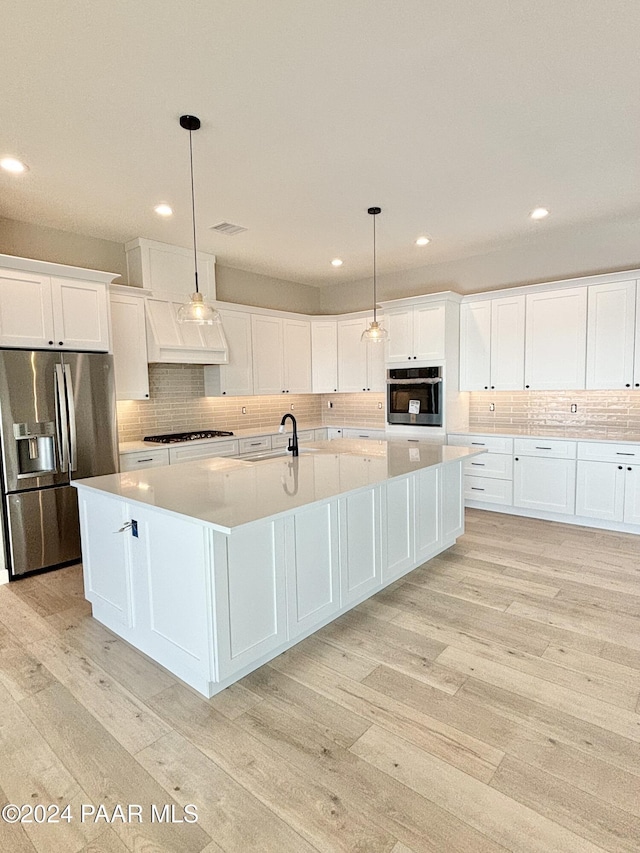 kitchen featuring white cabinets, light wood-type flooring, hanging light fixtures, and appliances with stainless steel finishes