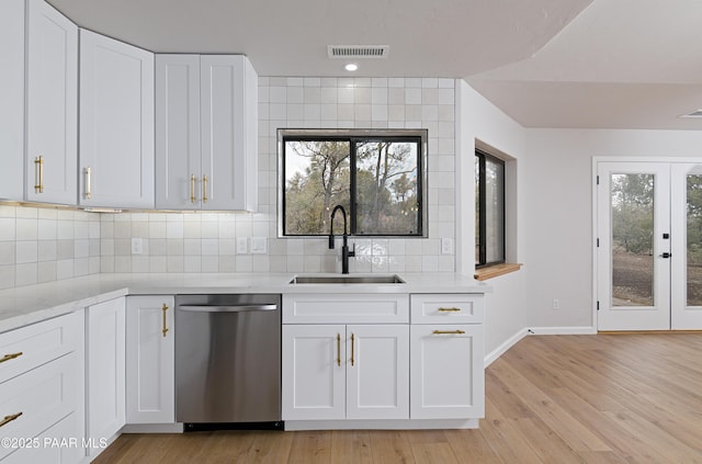 kitchen featuring visible vents, a sink, light wood-style floors, decorative backsplash, and dishwasher