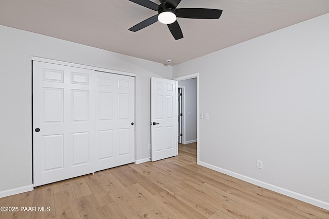 unfurnished bedroom with a closet, ceiling fan, light wood-type flooring, and baseboards