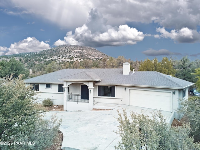 ranch-style home with driveway, covered porch, stucco siding, a chimney, and a garage