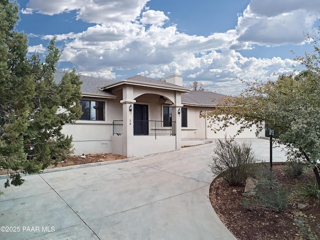 view of front of property featuring a shingled roof, stucco siding, a chimney, driveway, and an attached garage