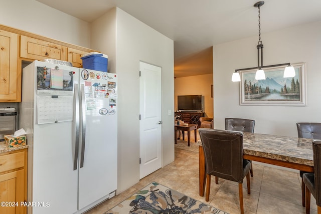 kitchen featuring light brown cabinets, white refrigerator, light tile patterned floors, and hanging light fixtures